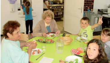 Ecoliers et anciens partagent le repas du midi dans la salle de la cantine. La cantine, un lieu intergénérationnel